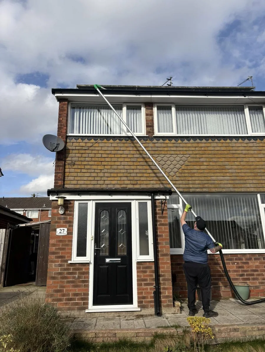 CJB cleaning upstairs windows with a water fed pole from the ground